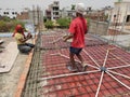 Poor labor workers are employed in a local household construction work. Iron rods are tied together before pouring concrete mixtur