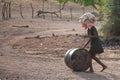Poor local kid walking with a barrel and clothes on her head in