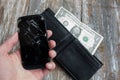 Poor man is holding in hand his crashed black smartphone. An empty black leather wallet with one dollar in it. No money to buy a Royalty Free Stock Photo