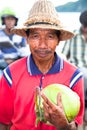 Poor man with staw hat selling a coconut