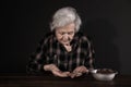 Poor mature woman with coins and bread in bowl