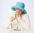 Poor Mature Woman Looks at Coin and Thinks with Hand Under Chin
