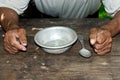 Poor old man`s hands and empty bowl on wooden background.An angry hungry man clenches his hands into fists. Royalty Free Stock Photo