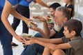 Poor people receiving food from volunteers near wall