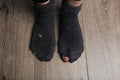 Poor person in shabby socks on wooden floor