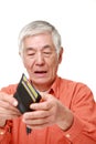 Poor senior Japanese man looking at his own empty wallet Royalty Free Stock Photo