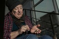 Poor senior man counting coins on stairs indoors