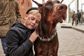 Poor street boy with dog doberman in city street Royalty Free Stock Photo