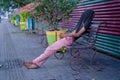 Poor tired depressed hungry homeless man or refugee sleeping on the wooden bench on the urban street in the city