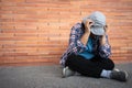 Poor tired stressed depressed elderly Asian woman homeless sitting on the street in the shadow of the building and begging for Royalty Free Stock Photo