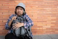 Poor tired stressed depressed elderly Asian woman homeless sitting on the street in the shadow of the building and begging for