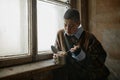 Poor unhappy young woman eating canned food against window