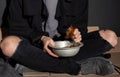 Poor woman with bread sitting on floor near wall, closeup