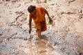 Poor woman fishing around a muddy place