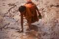 Poor woman fishing around a muddy place