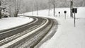 Poorly cleared country road in hilly winter landscape with dense high snow cover