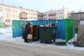 Russia, Novosibirsk, February 23, 2019: poorly dressed unemployed woman pensioner looking for garbage cans scraps and garbage