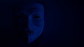 Poorly visible mask on a dark background in blue. An anonymous hacker or halloween party symbol. Copy space. Shooting a subject in