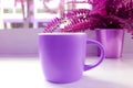 Vivid purple colored coffee mug with potted ferns on a table