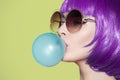 Pop art woman portrait wearing purple wig. Blow a blue bubble Royalty Free Stock Photo