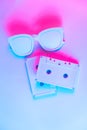 Pop culture, retrowave. Audio cassette on glowing duotone background. Neon red blue light.