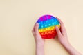 Pop it. Girl playing with trendy popular rainbow colorful anti stress toy. Close up