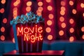 Popcorn box with neon Movie Night sign, vibrant red and bokeh background entertainment? Royalty Free Stock Photo