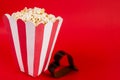 Popcorn box on red background and film in the form of heart with space for text Royalty Free Stock Photo