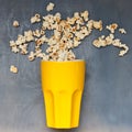 Popcorn chaotic jumps from big yellow cup on blue background Royalty Free Stock Photo