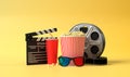 Popcorn, 3D glasses, film reel and clapboard on a yellow background. Minimalist creative concept