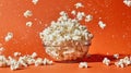Popcorn exploding and flying out of a clear glass bowl against a vibrant orange background Royalty Free Stock Photo