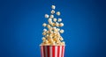 Popcorn exploding out of a red and white striped bucket against a vibrant blue background Royalty Free Stock Photo