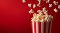 Popcorn falling into a red and white striped container on red background Royalty Free Stock Photo