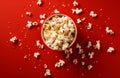 popcorn falling with small corn kernels in colorful bowl on red background Royalty Free Stock Photo