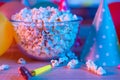 Popcorn with festive accessories on the background of TV. Watching TV on the occasion of a family celebration or in a circle of