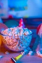 Popcorn with festive accessories on the background of TV. Watching TV on the occasion of a family celebration or in a circle of