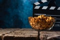 Popcorn film reel and movie clapper on wood background. Screensaver for the inscription of the rest of the viewing of films. Royalty Free Stock Photo