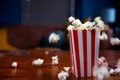 Popcorn flying out of cardboard box. red and white striped popcorn bucket with flying popcorn in the living room, movie or cinema