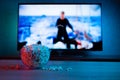 Popcorn in a glass plate on the background of the TV. Color bright lighting, blue and red. Background Royalty Free Stock Photo