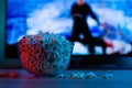 Popcorn in a glass plate on the background of the TV. Color bright lighting, blue and red. Background Royalty Free Stock Photo