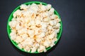Popcorn in a green bowl on a black background.