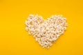 Popcorn in heart shape on yellow background, top view Royalty Free Stock Photo
