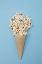 Popcorn ice cream in a cone on a light blue background. minimal flat lay scene