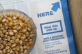 Popcorn kernels in a cup on a microwave bag of popcorn Royalty Free Stock Photo