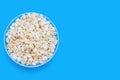 Popcorn in a large glass bowl on a blue background with a top view Royalty Free Stock Photo