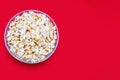 Popcorn in a large glass bowl on a red background from a top view Royalty Free Stock Photo