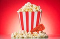 Popcorn in large square box and around, movie ticket on bright r