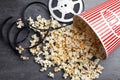 Popcorn and movie reel on grey stone table. Cinema snack