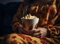 Popcorn paper bucket in the hands of a young girl preparing to watch a movie. Showtime. Eating delicious unhealthy sweet Royalty Free Stock Photo