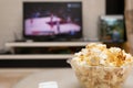 Popcorn and remote control on sofa with a TV broadcasting basketball match